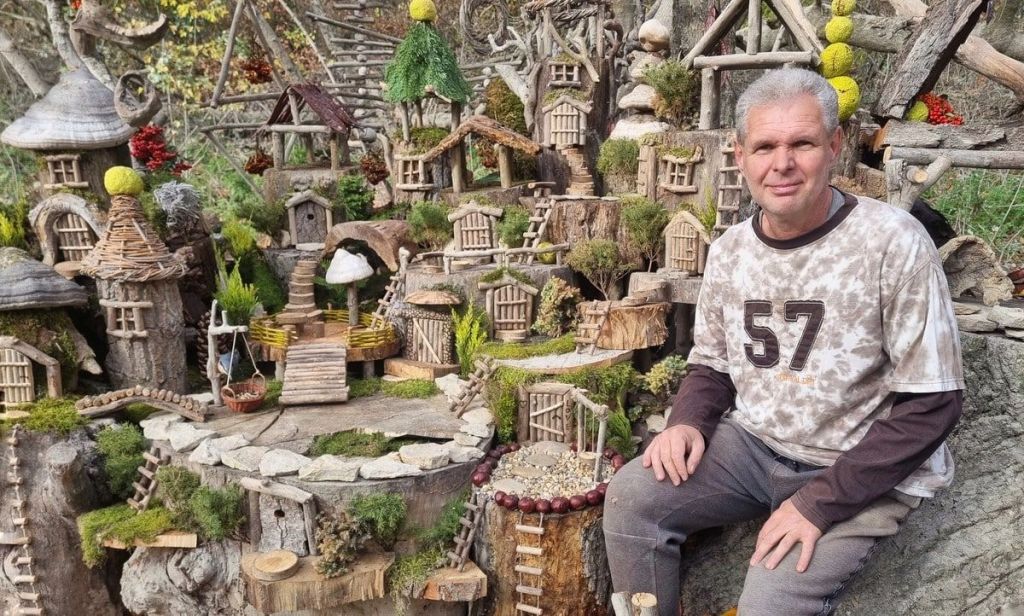 Egy apró, kézzel készített manóház fa ágai között, moha és természeti elemek között elrejtve; Kánya Tamás alkotása a budakalászi Manófalván.